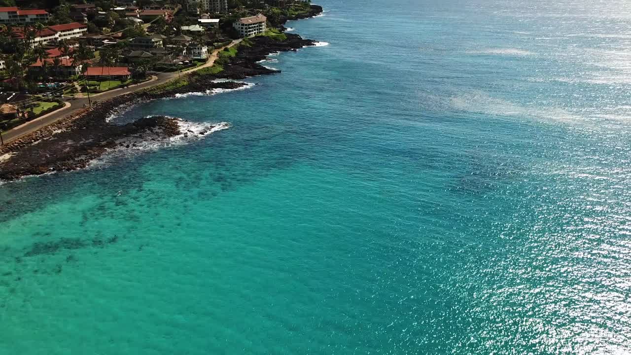 Ripresa estesa con drone che vola lungo il lungomare di Poipu a Kauai, Hawaii, di giorno.