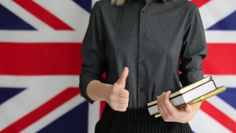 person with books giving thumbs up in front of the uk flag