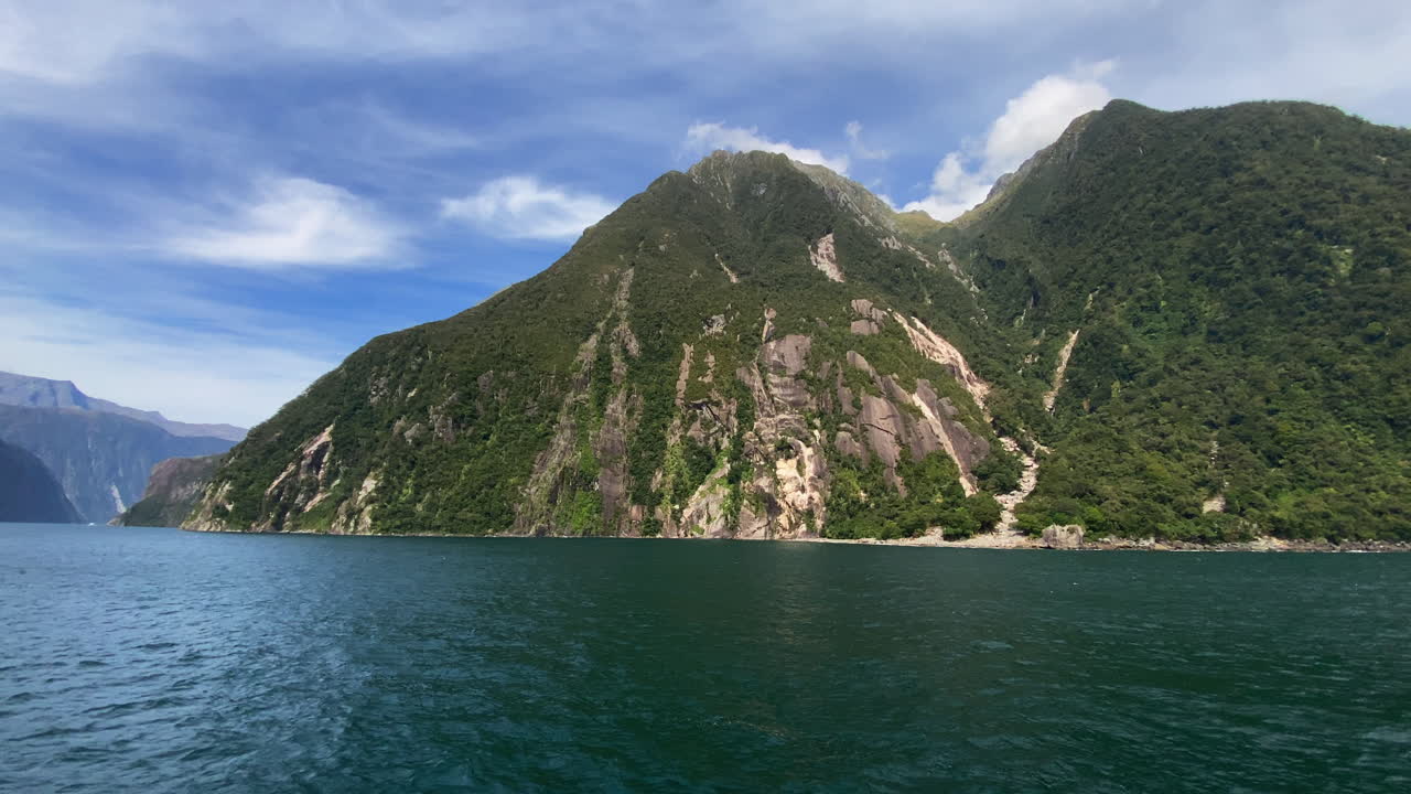 Milford Sound cruise, pan view of green mountains in Fiordland National Park, New Zealand