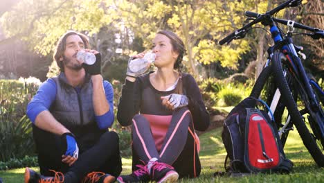 Mountain-biking-couple-drinking-water-in-the-forest