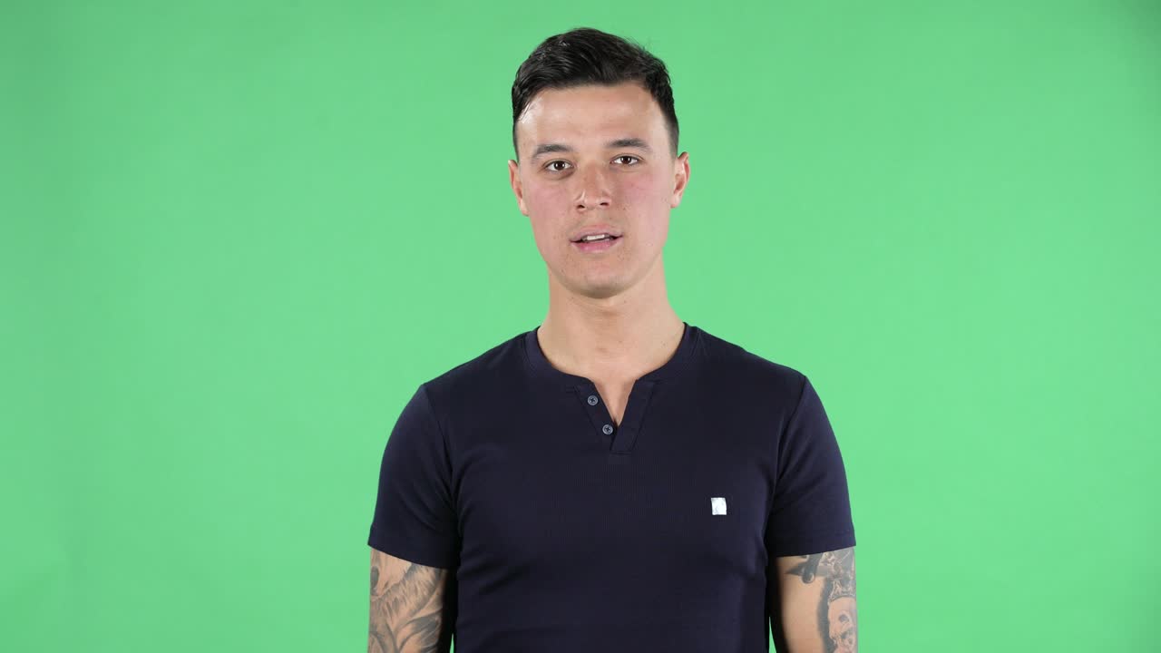 똑바로 웃고 심장 몸짓과 공기 키스를 보여주는 잘생긴 젊은 남자의 초상화. 녹색 화면