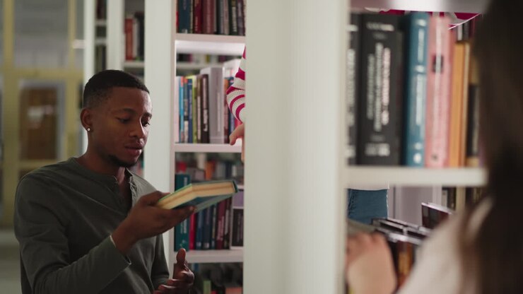 Reader takes books from librarian by bookshelves. African American student gets literature for essay with friend help in college storage. Education sources