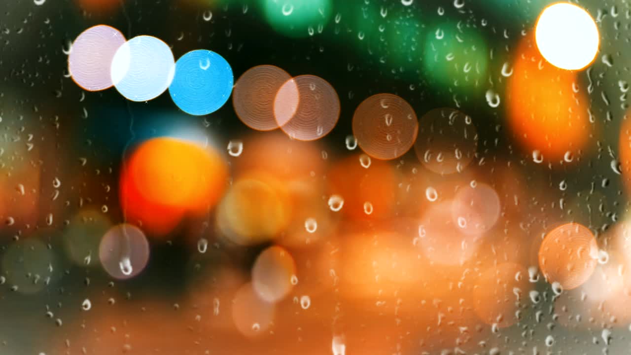 gotas de lluvia cayendo en la ventana de vidrio en el fondo urbano hermoso efecto de luz bokeh de colores.