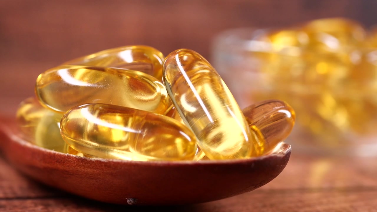 Capsule dorate di olio di pesce Omega 3 in un cucchiaio di legno