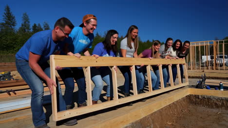 group of volunteers lifting a wooden frame at a construction site