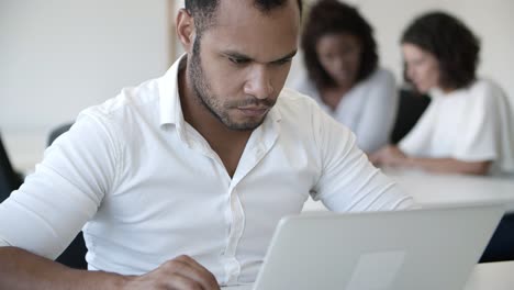 Concentrated-handsome-programmer-working-with-laptop