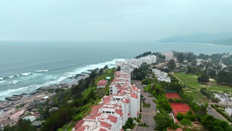 Luftbildwagen-In-Exklusiven-Gebäuden-Mit-Ziegeldächern-Mit-Blick-Auf-Das-Meer,-Bewölkter-Tag,-Maitencillo,-Chile