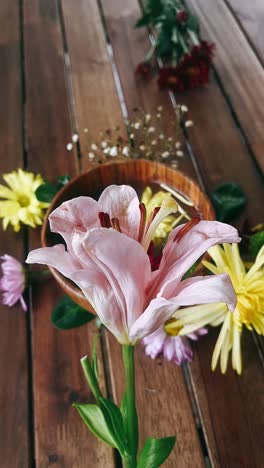 pink lily and colorful flowers arrangement on wooden table