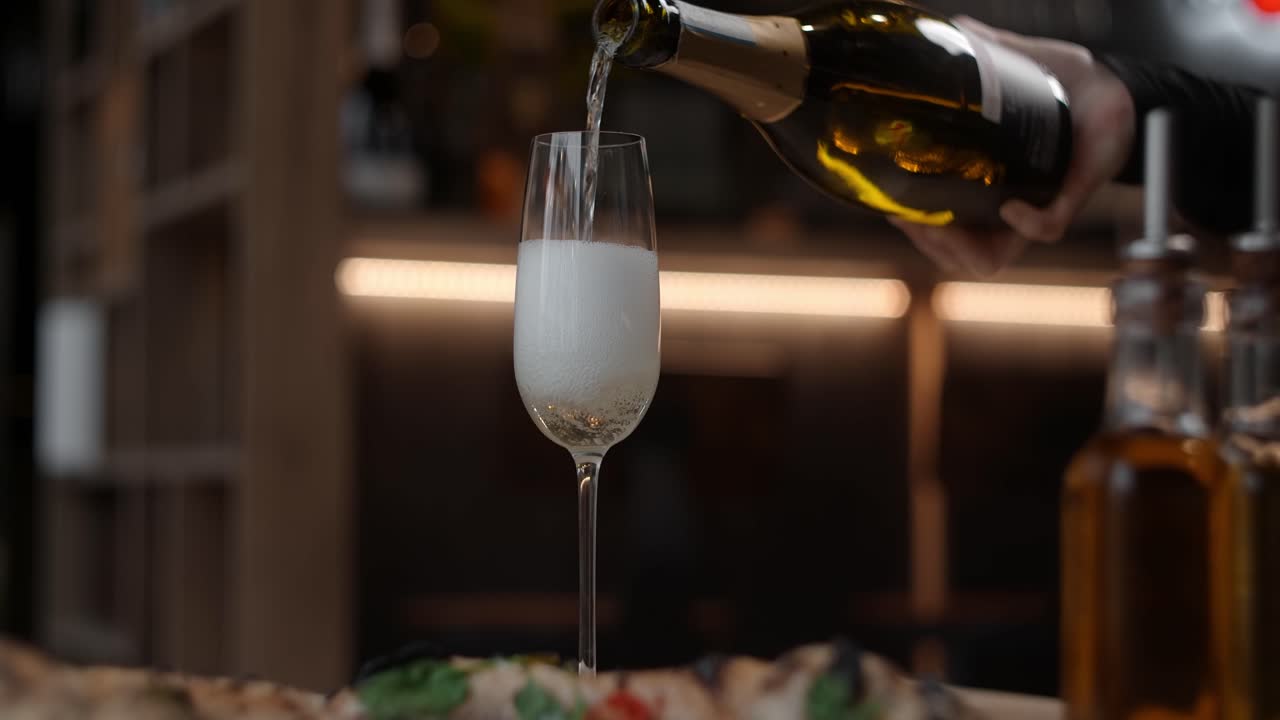 Versare champagne in un bicchiere in un ristorante con pizza