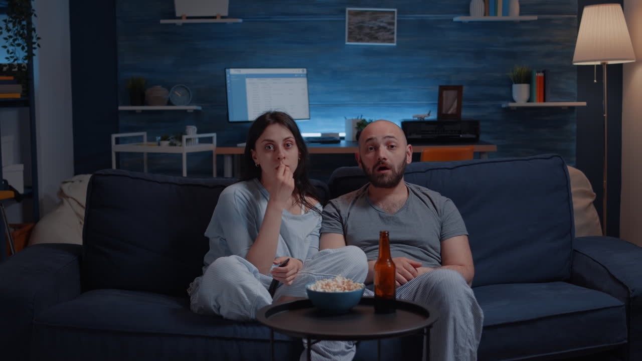 Coppia sorpresa che guarda un film in TV di notte e mangia popcorn