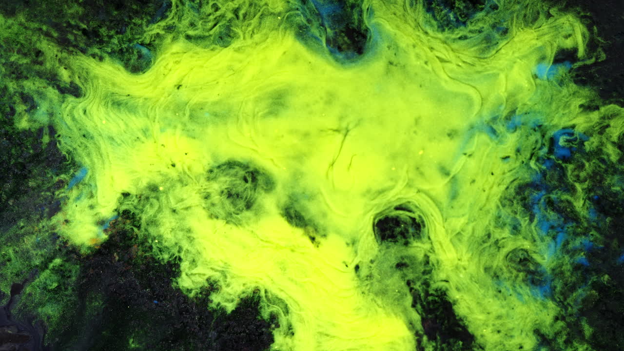 Bright neon liquids swirl and mix in macro view, creating an abstract visual effect