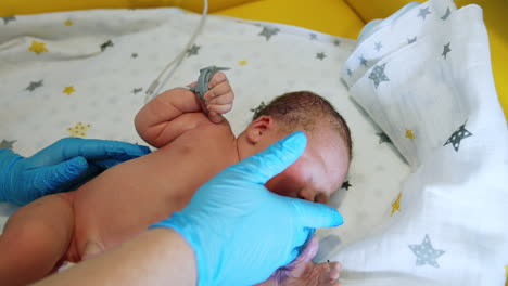 nurse taking care of a newborn caucasian baby. cute child winking from a bright light. close up.