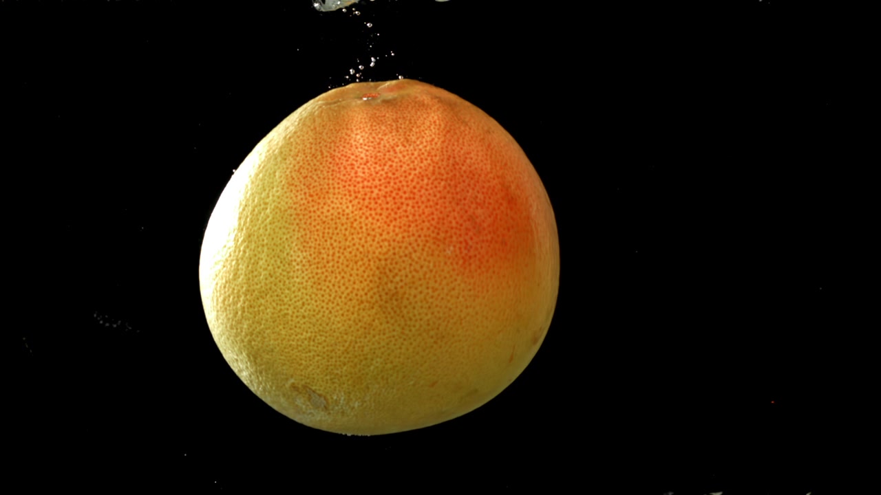 Rallentatore di pompelmo che affonda nell'acqua con bolle