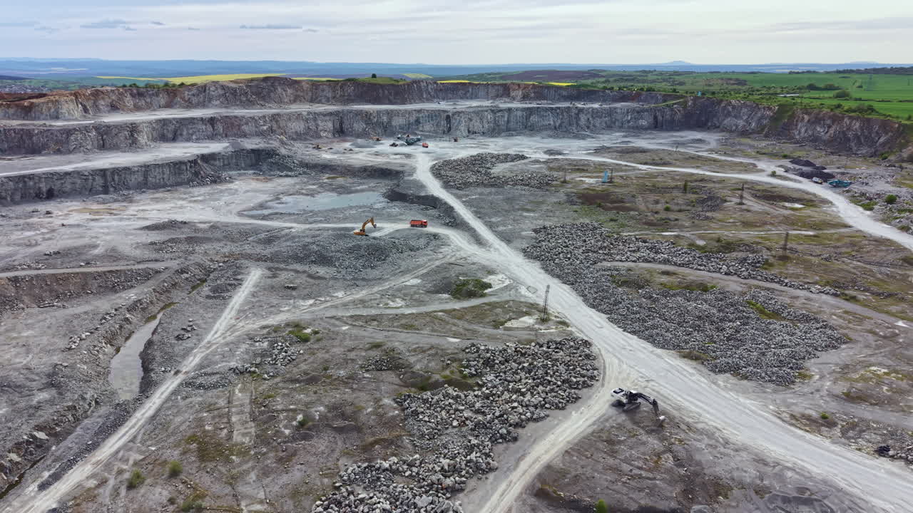 Excavation process at a stone quarry in a rural area during a cloudy day with machinery working on site