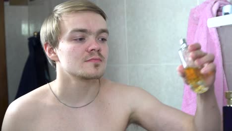 young man applying perfume in bathroom