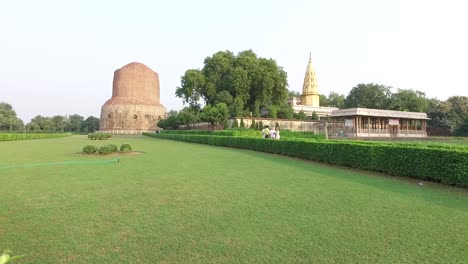 Una-Amplia-Toma-Panorámica-Panorámica-Con-Vistas-Al-Césped-Verde-En-La-Estupa-Dhamek-En-Varanasi,-India