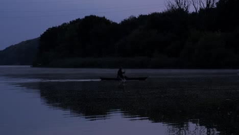 a man floats in a boat on the river at dusk. horror.