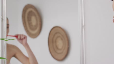 Biracial-woman-with-band-brushing-teeth-in-bathroom