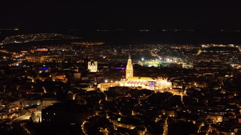 70mm drone filming of the city of toledo at night, we see its cathedral as a central element very illuminated, since it is a landmark icon, the lights create that magic through its night streets.
