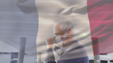 animation of flag of france waving over caucasian man wearing face mask in city street