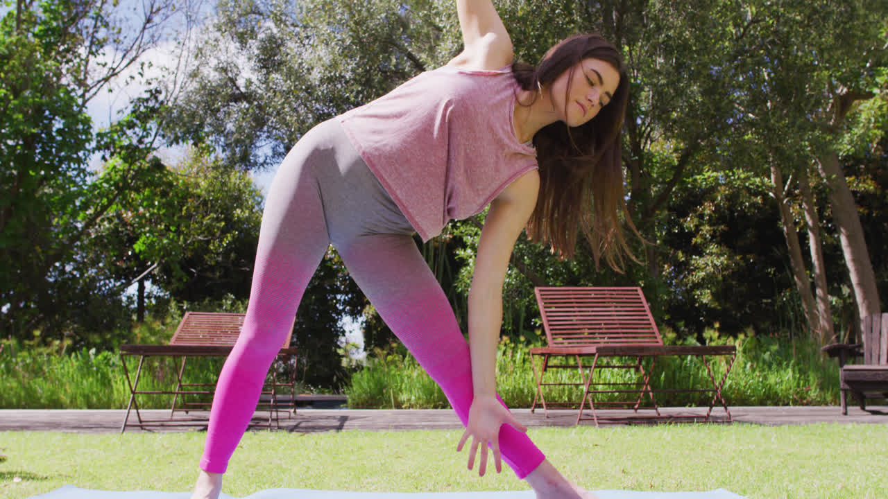 feliz mujer caucásica practicando yoga de pie en un parque soleado