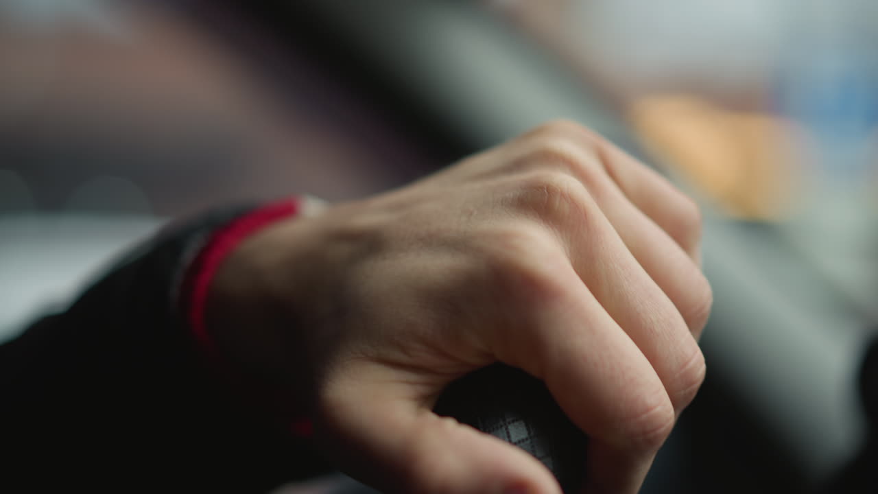 Close up shot of commuter holding firm steering wheel with one hand, rotating wheel smoothly while driving through urban street, focus on textured leather grip and wrist movement inside car cabin