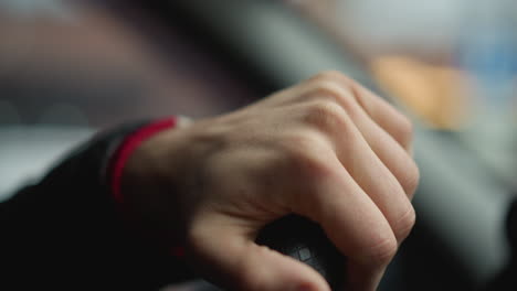 close up shot of commuter holding firm steering wheel with one hand, rotating wheel smoothly while driving through urban street, focus on textured leather grip and wrist movement inside car cabin