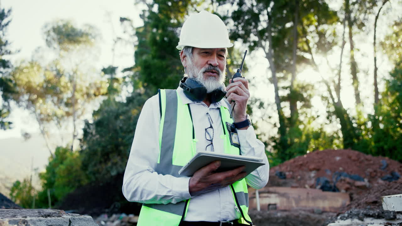 Construction worker on site using walkie-talkie and tablet