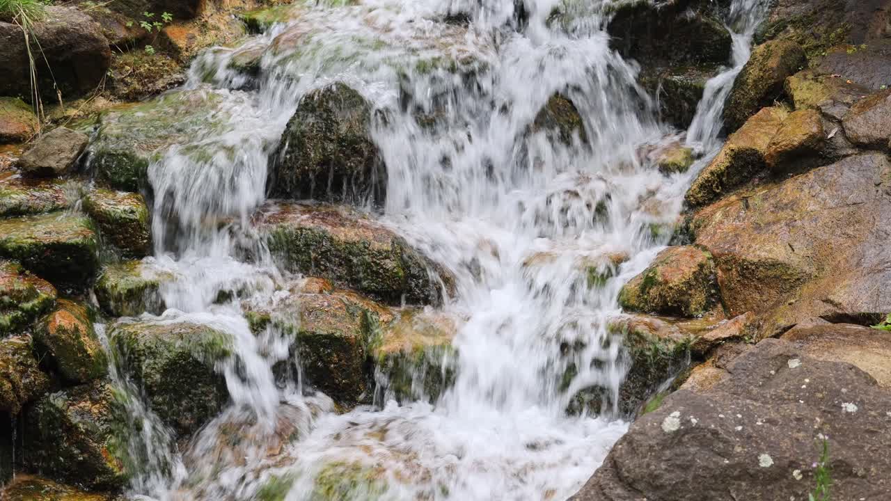 A stream of water flows over rocks, creating a peaceful and serene atmosphere