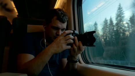 man stocker in train listening to music and making footage