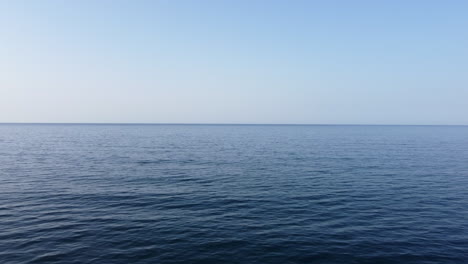 flying low over wide blue ocean under clear bright sky