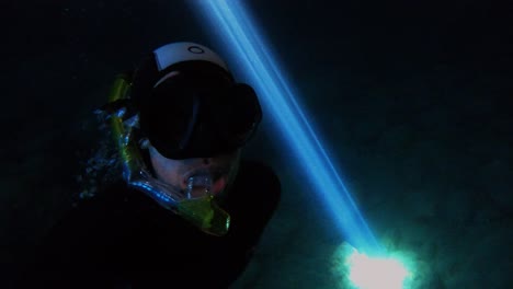 Scuba diver exploring the mysterious underwater scenery of a natural beam of sun light illuminating the dark waters of a sea cave with, Vis island, Adriatic Sea, Croatia