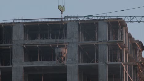 detailed view of a multi-story building under construction with exposed structural elements and a crane