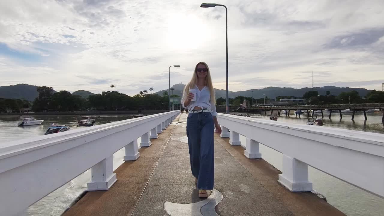 Woman Walking on a Pier with a Coffee