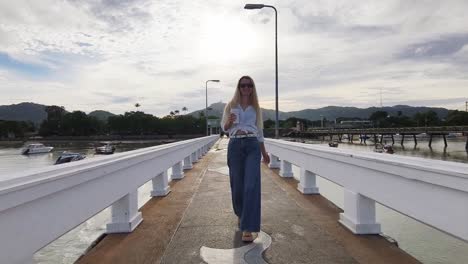 woman walking on a pier with a coffee