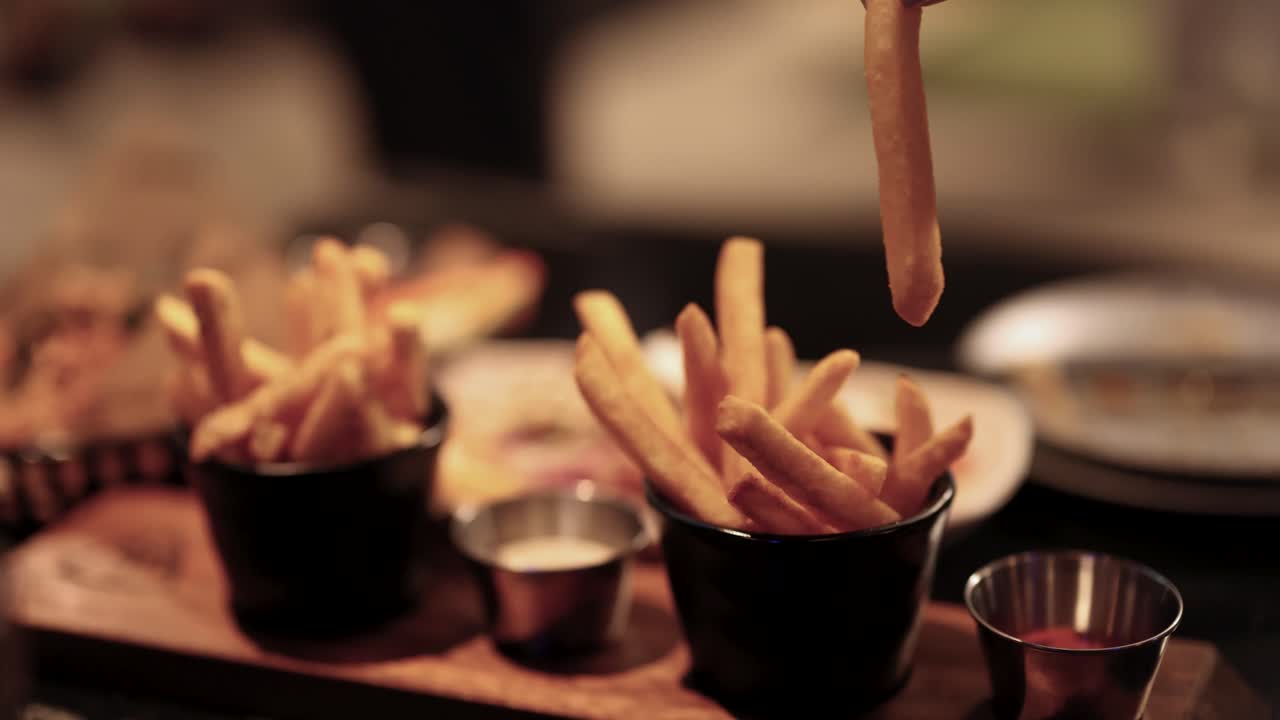 Hand dipping fries into sauce at driving range