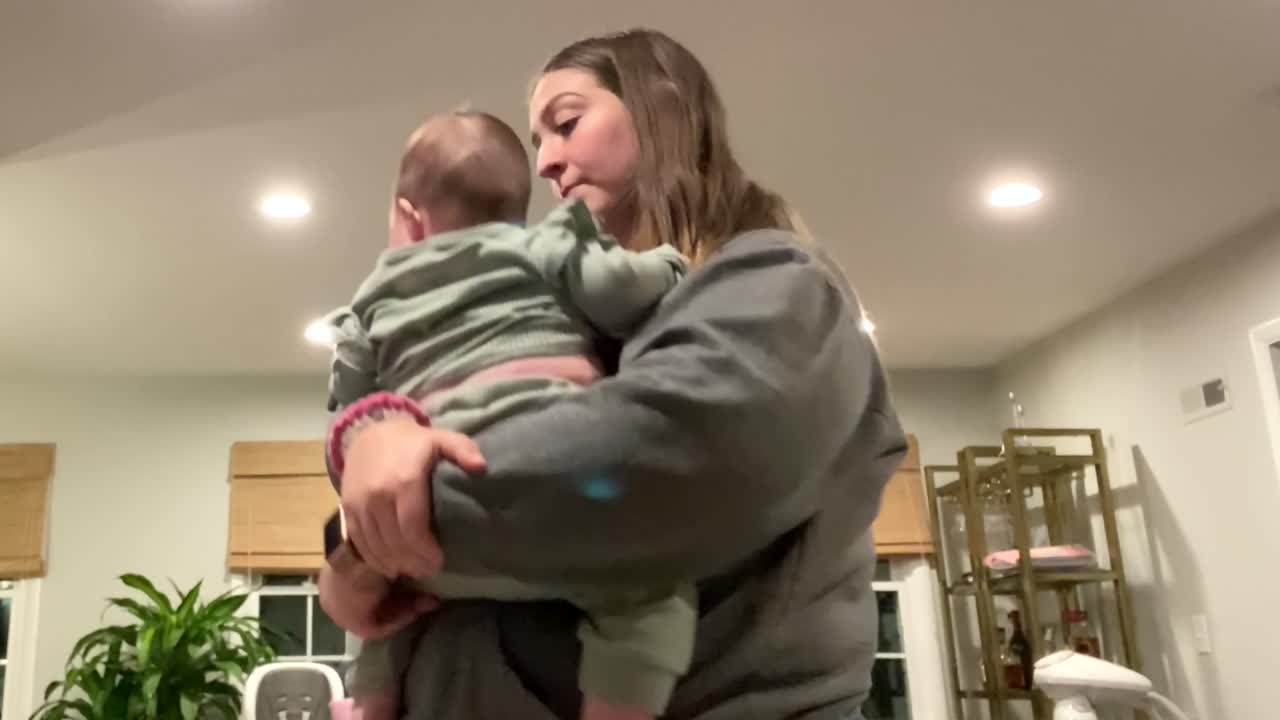 Jeune baby-sitter tenant, faisant rebondir et jouant avec un petit bébé en le soulevant doucement dans les airs
