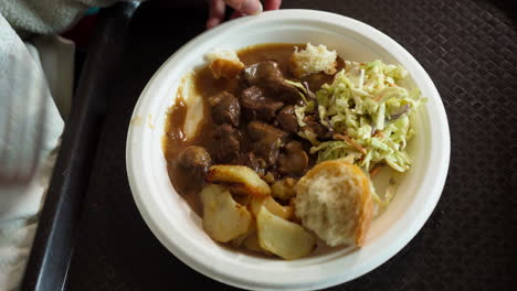serving of delicious caribou stew on plate with veggies and bread on side. high angle shot