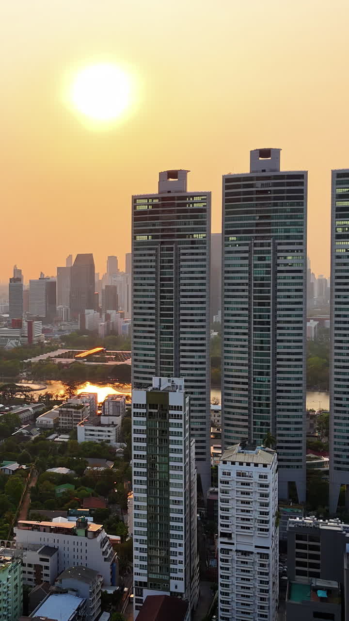 Vista aérea de drone do horizonte de Bangkok ao pôr do sol com edifícios modernos de grande altura e luz dourada do entardecer. Vertical