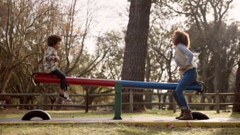 mother and child playing on see-saw in park