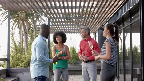 equipo de diversos colegas felices tomando bebidas y hablando entre sí en el balcón de la oficina