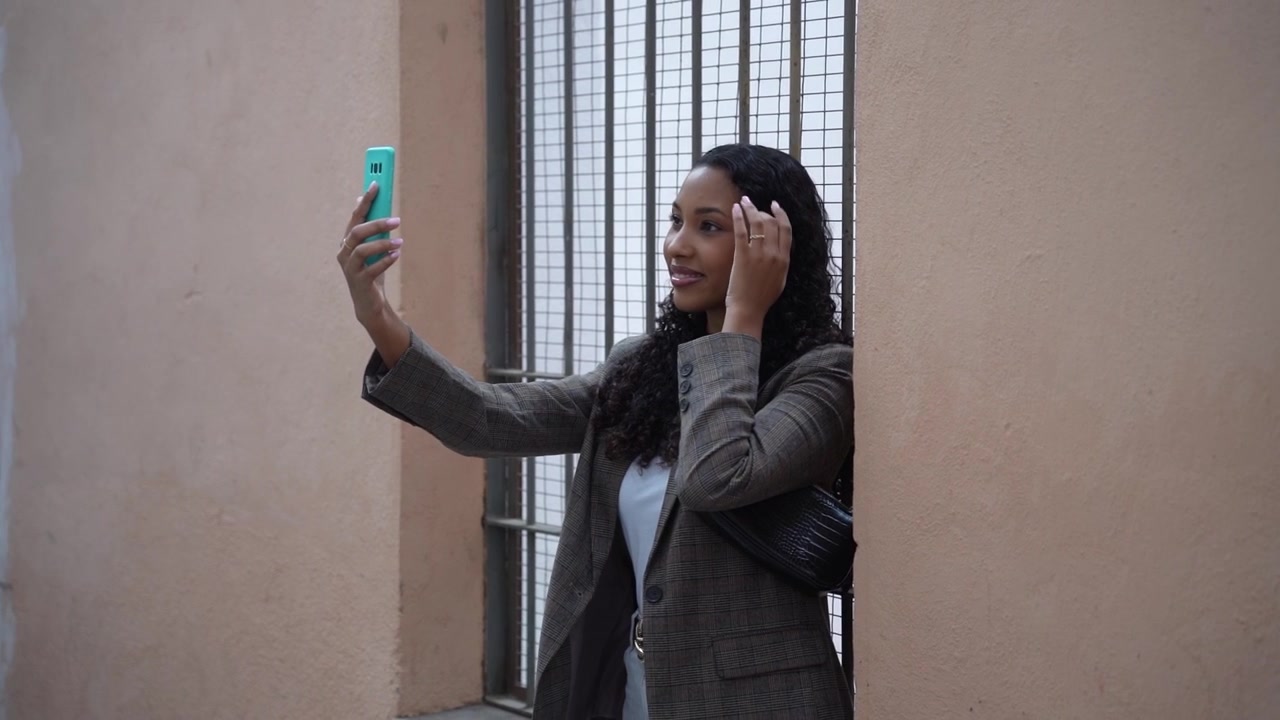 A young woman is taking a selfie against a colorful wall in a vibrant urban setting