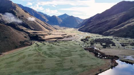 aerial footage captures lake moke's serene landscape in queenstown, new zealand, with lush greenery and mountain views under soft daylight