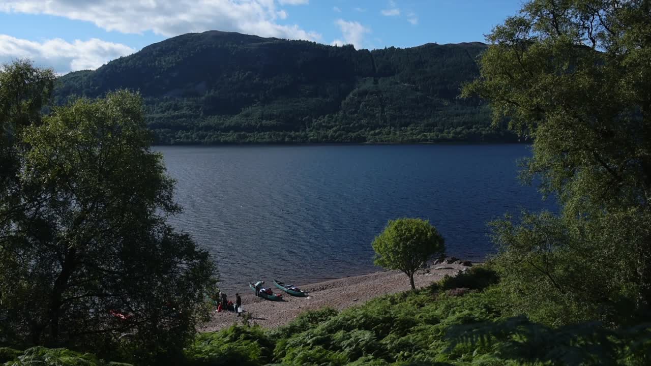 Loch Ness landscape behind some trees, Scotland, with mountains in the background