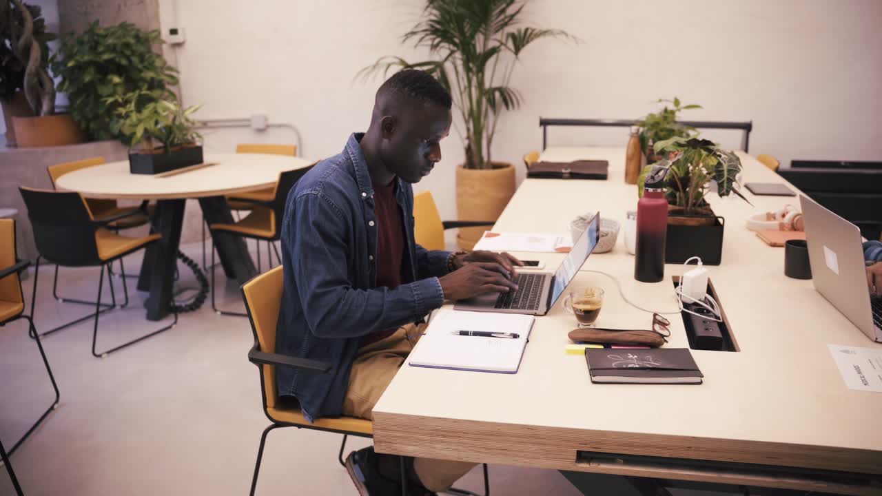 Black man taking notes and working on a laptop