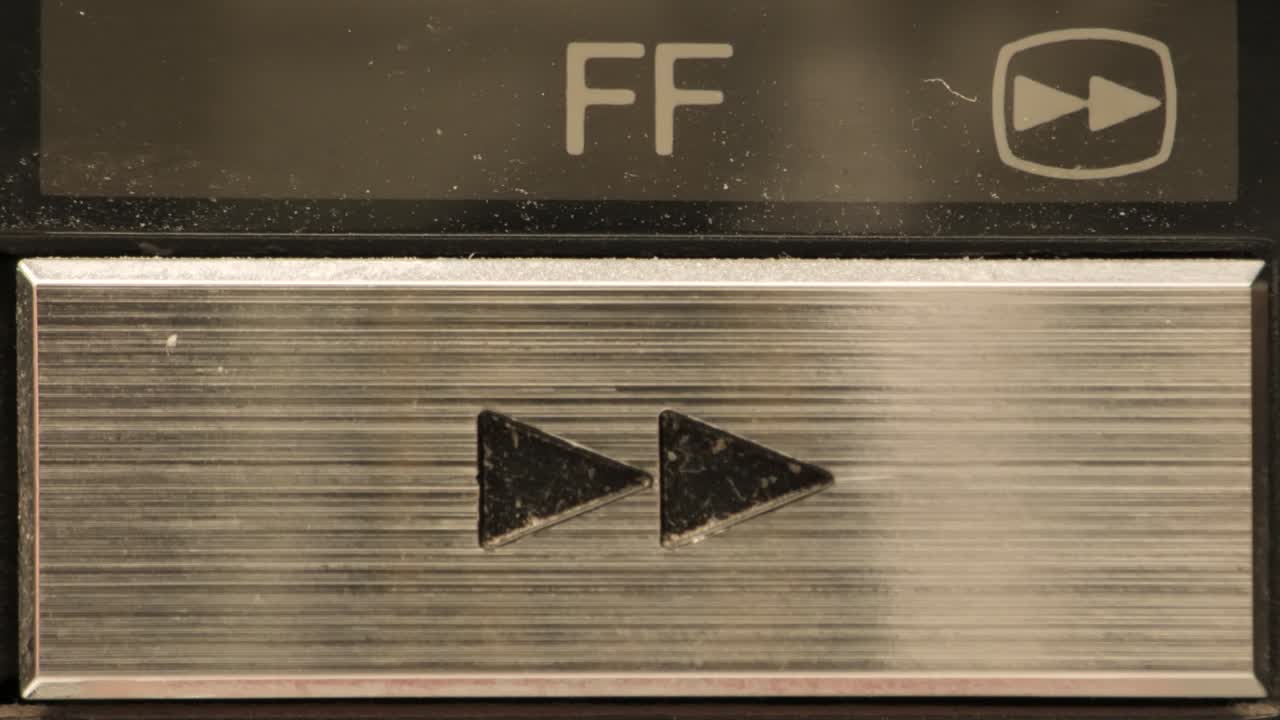 Extreme close up of buttons on an old antique or vintage VCR Pushing the fast forward button