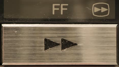 Extreme-close-up-of-buttons-on-an-old-antique-or-vintage-VCR-Pushing-the-fast-forward-button