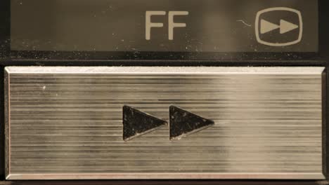 extreme close up of buttons on an old antique or vintage vcr pushing the fast forward button