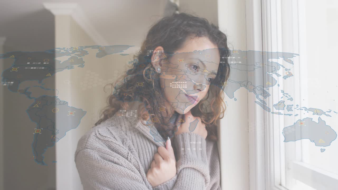 Woman adjusting sweater by window and initiating world map data overlay visualizing global network