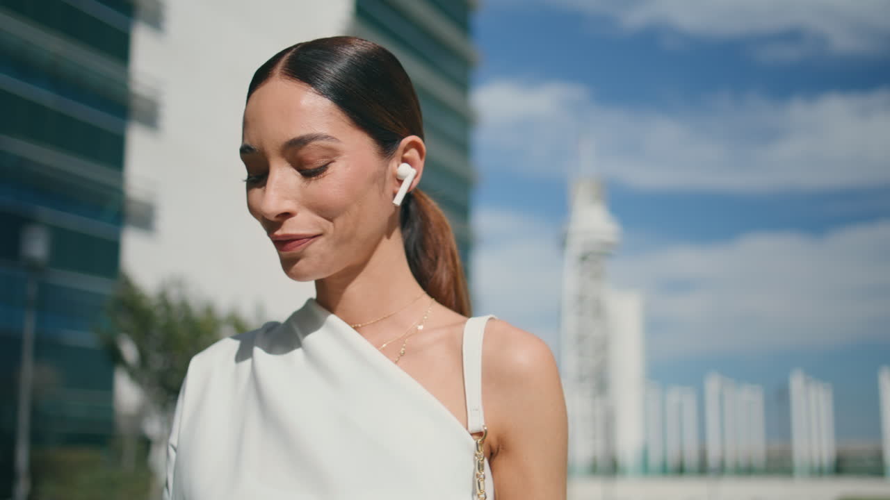 mulher de negócios fones de ouvido a falar ao telefone a caminhar na rua de perto.